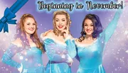 Three smiling women dressed in matching blue, sparkly outfits with white fur trim are posing against a festive background with text stating 