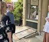 A woman in historical costume is speaking to two attentive listeners on a sidewalk possibly conducting a historical tour