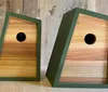 The image shows three wooden birdhouses with different color accents set against a rustic wooden background