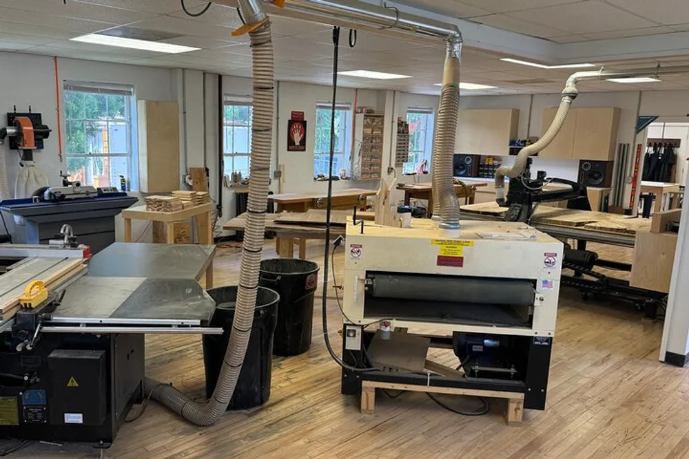 The image shows a well-equipped woodworking shop with various machines like saws and sanders connected to dust extraction systems