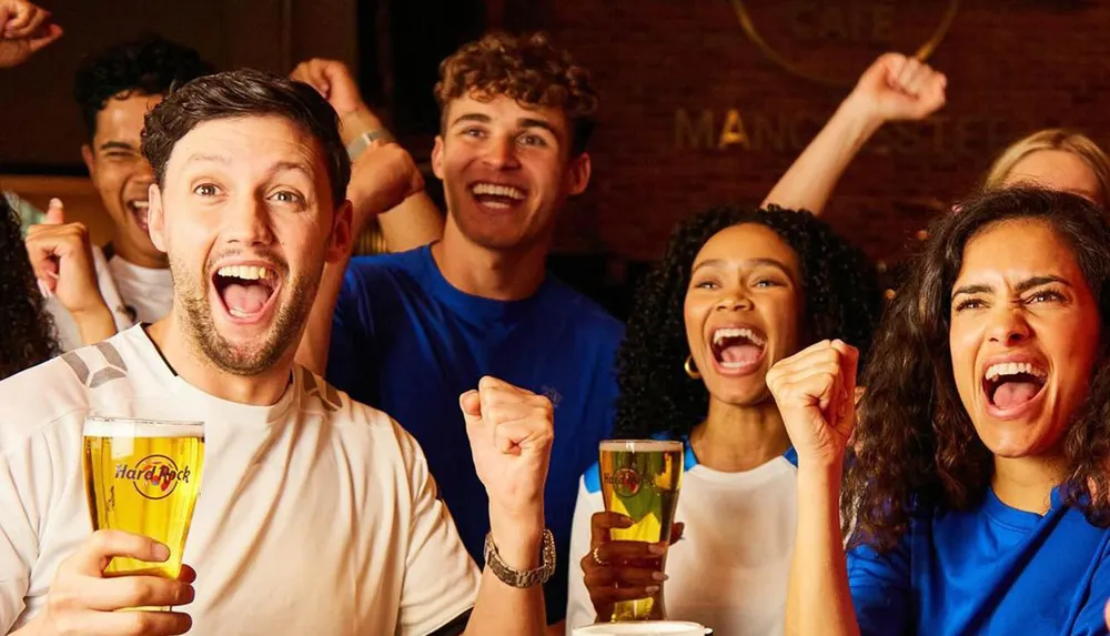 A group of jubilant people are celebrating with drinks and cheers possibly watching a sports event or celebrating a victory