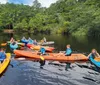 Three people are kayaking in a scenic waterway surrounded by trees with some showing autumnal colors