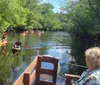 A group of people is enjoying a scenic boat tour on a calm river amidst a forested area