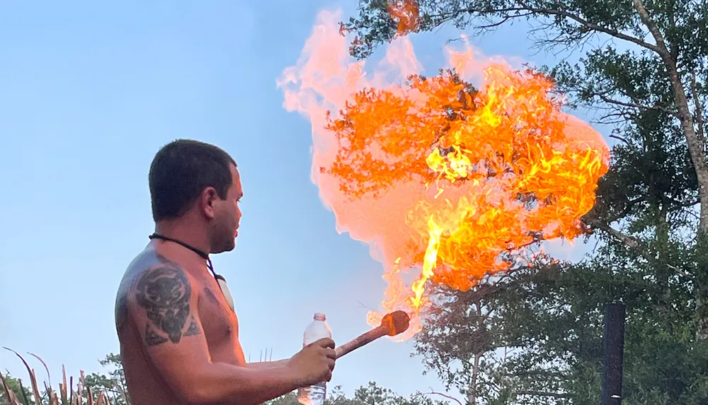 A person is performing a fire-breathing act emitting a large plume of flame from their mouth into the air