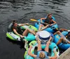 A group of people are enjoying a sunny day on the water floating in individual inflatable rafts tied together