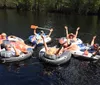 A group of people are enjoying a sunny day on the water floating in individual inflatable rafts tied together