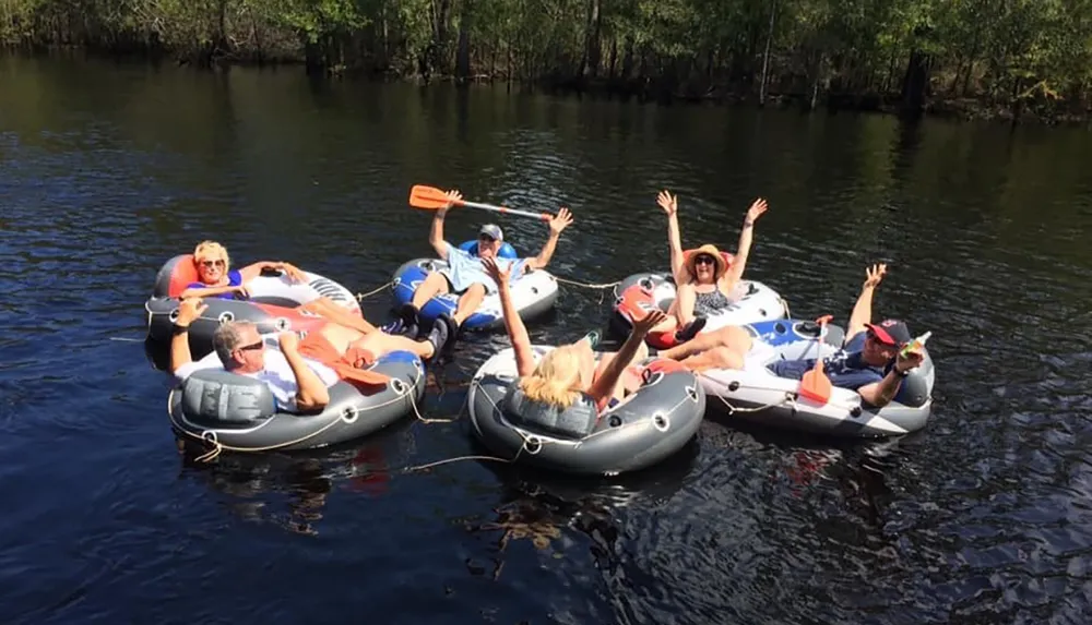 A group of people are enjoying a sunny day on the water floating in individual inflatable rafts tied together