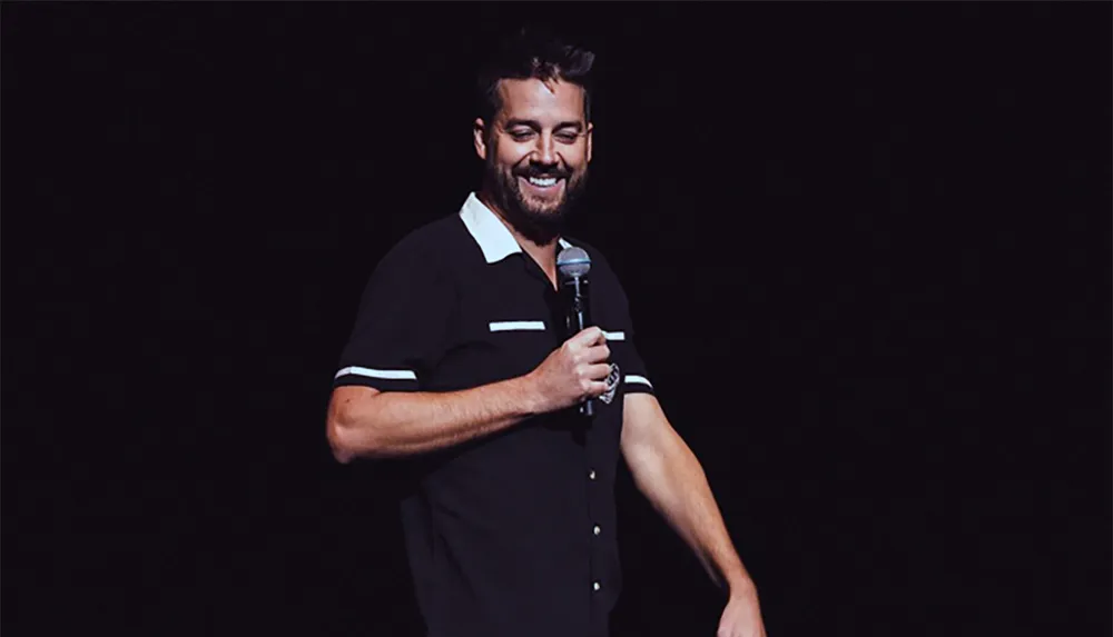 A man is smiling while holding a microphone on stage