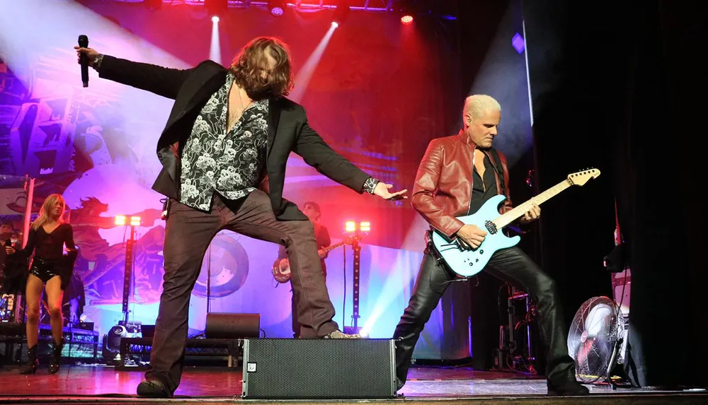 A lively rock band performing on stage under dramatic lighting with a singer and guitarist in the foreground