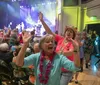 A saxophonist in a tropical shirt plays energetically among an audience at a lively indoor concert