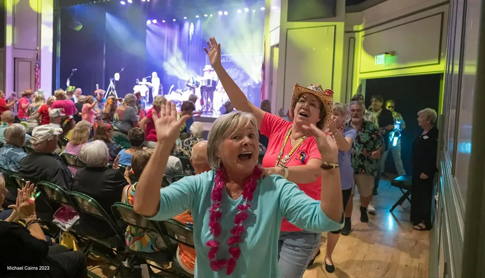 People are joyfully dancing in a conga line at a lively indoor concert