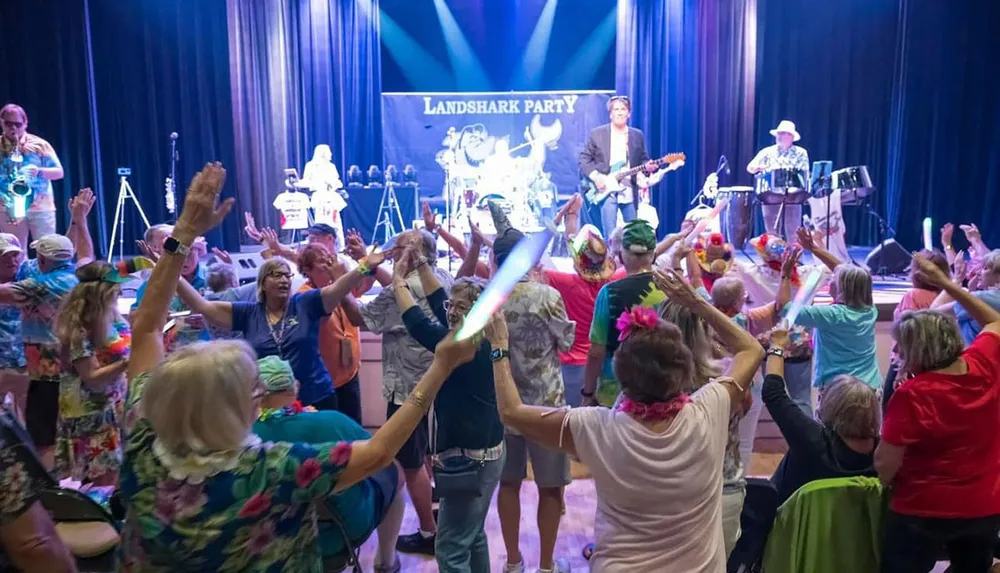 A lively crowd dances enthusiastically in front of a band performing on stage