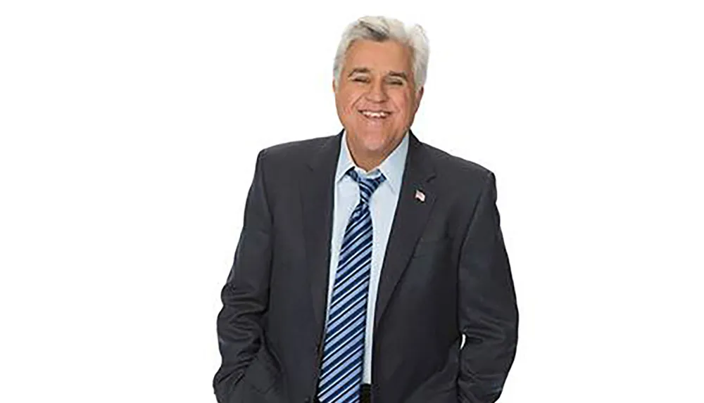 A smiling man in a suit with a striped tie poses against a plain white background