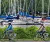 A person wearing blue jeans and white sneakers is riding a black electric bicycle on a city street