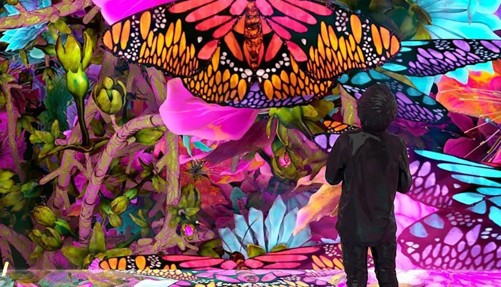 A person stands in a vibrant colorful surreal scene filled with oversized butterflies and lush fantastical foliage