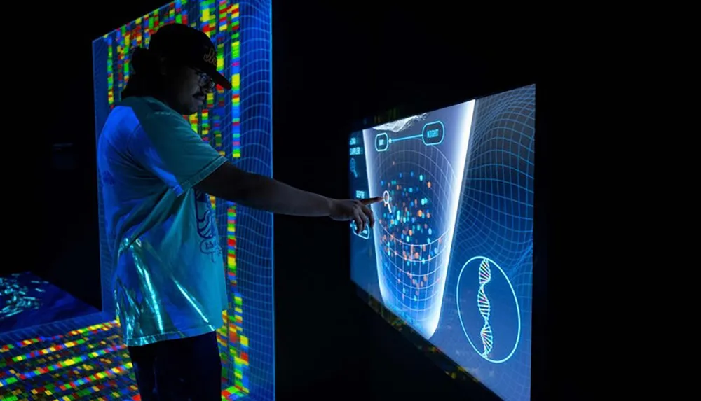 A person is interacting with a large brightly lit touchscreen display showing colorful data and a DNA graphic