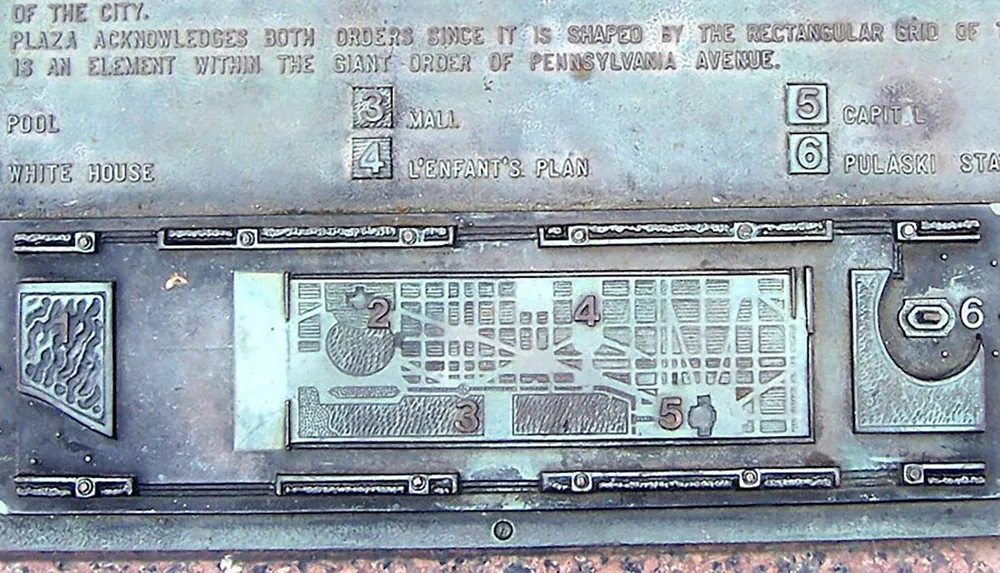 The image shows a bronze map plaque depicting key locations in a city including the White House the Mall the Capitol LEnfants Plan and Pulaski Statue