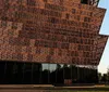 The image features the modern architectural design of the National Museum of African American History and Culture with the Washington Monument visible in the background