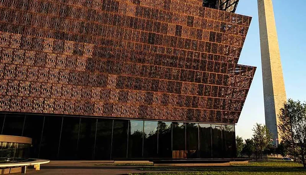 The image features the modern architectural design of the National Museum of African American History and Culture with the Washington Monument visible in the background