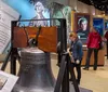 Visitors are exploring a museum exhibit featuring the Liberty Bell with historical displays in the background