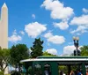 A hop-on hop-off tour trolley passes in front of the US Capitol building on a sunny day