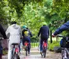 A group of people wearing bright green helmets are cycling along a tree-lined path