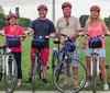 A group of people wearing bright green helmets are cycling along a tree-lined path