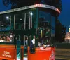 A trolley tour bus with passengers is parked at night near a brightly lit Capitol building