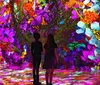 Two people stand in a vibrant immersive environment filled with colorful flowers and butterflies