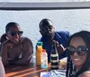 A group of friends wearing sunglasses are enjoying drinks at a table by the water