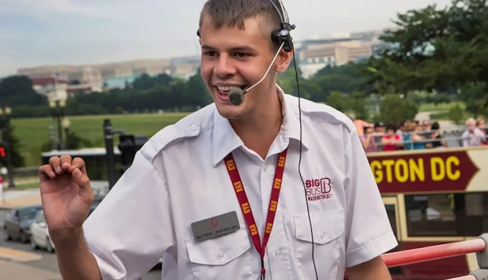 A tour guide in a Big Bus Washington DC uniform uses a headset microphone while engaging with an audience