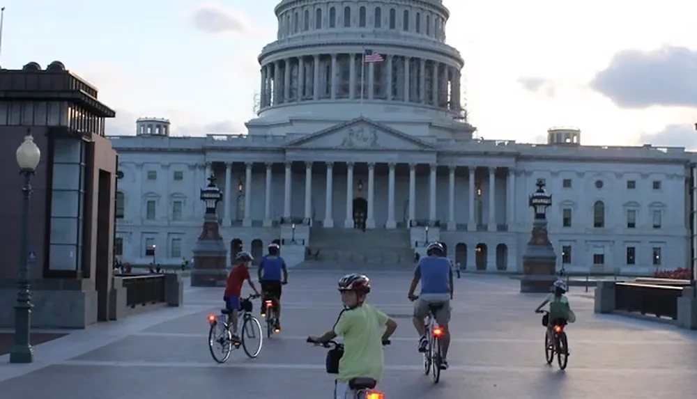 A group of people on bicycles ride towards the US Capitol building