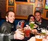 A group of people are joyfully clinking glasses in a bar setting